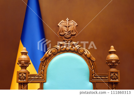 Constitutional Court of Ukraine law justice system. Empty chair judge Ukraine flag in courtroom background. Trial court scales of justice symbol Ukraine justice reform 111860313