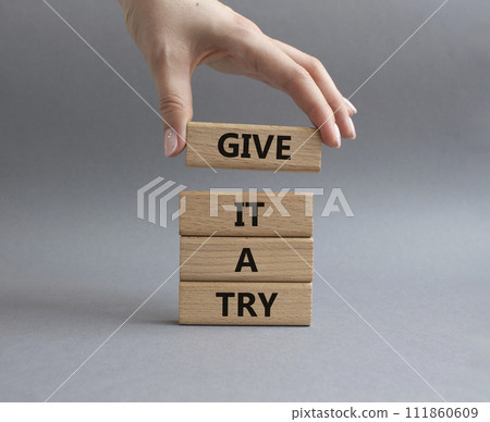 Give it a try symbol. Concept words Give it a try on wooden blocks. Beautiful grey background. Businessman hand. Business and Give it a try concept. Copy space. 111860609