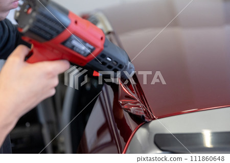 Wrapping a new foil to a car by heat gun, gluing a new foil, detailing concept 111860648