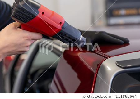 Wrapping a new foil to a car by heat gun, gluing a new foil, detailing concept Wrapping a new foil to a car by heat gun, gluing a new foil, detailing concept 111860664