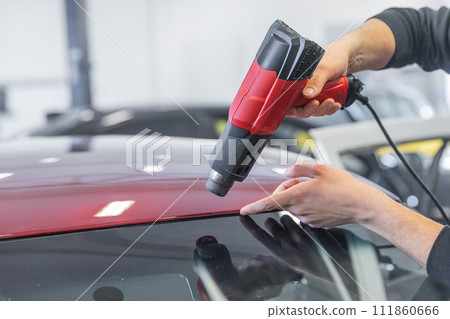 Wrapping a new foil to a car by heat gun, gluing a new foil, detailing concept 111860666