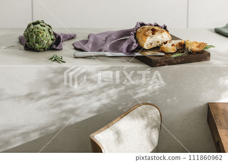 Sliced bread on wooden board, artichoke and stainless still kitchen knife. Kitchen aesthetic concept Sliced bread on wooden board, artichoke and stainless still kitchen knife. Kitchen aesthetic concept 111860962