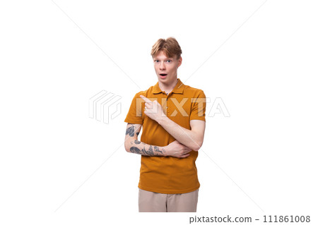 young red-haired man with a short haircut and a tattoo on his arm is dressed in a yellow t-shirt young red-haired man with a short haircut and a tattoo on his arm is dressed in a yellow t-shirt 111861008