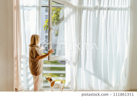Peaceful relaxed mature woman enjoying morning fresh air and cup of coffee. Happy thoughtful 50s lady relaxing at open window, planning day. drinking hot beverage. 111861351