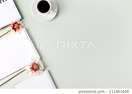 Composition with opened blank notepad, cup of black coffee, dahlia flowers on a gray background. Festive office desktop concept. Morning coffee cup. Composition with opened blank notepad, cup of black coffee, dahlia flowers on a gray background. Festive office desktop concept. Morning coffee cup. 111861600