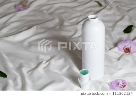 Ecological laundry detergent among orchid flowers on bed linen Ecological laundry detergent among orchid flowers on bed linen 111862124