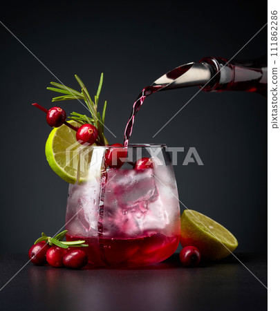 Cranberry cocktail garnished with berries, lime, and rosemary. Cranberry cocktail garnished with berries, lime, and rosemary. 111862286