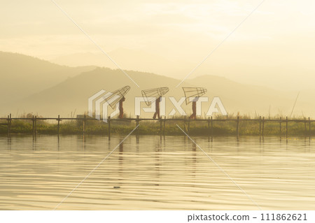Burmese fisherman casting or throwing a net for catching freshwater fish in Unle lake, natural river in Asia in Myanmar. People lifestyle. Burmese fisherman casting or throwing a net for catching freshwater fish in Unle lake, natural river in Asia in Myanmar. People lifestyle. 111862621