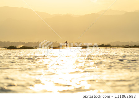 Burmese fisherman casting or throwing a net for catching freshwater fish in Unle lake, natural river in Asia in Myanmar. People lifestyle. 111862688