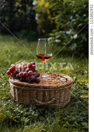a glass of dry rose wine from ripe grapes with a wicker basket in a vineyard 111862932