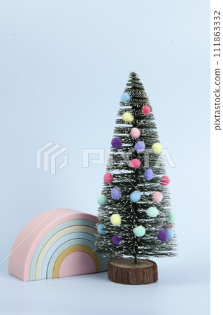 miniature christmas tree decorated with pompoms as baubles with a plastic rainbow toy next to him miniature christmas tree decorated with pompoms as baubles with a plastic rainbow toy next to him 111863332