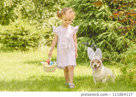Family Easter egg hunt. Girl and dog gather colorful eggs in bascket Family Easter egg hunt. Girl and dog gather colorful eggs in bascket 111864117