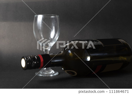 Bottle of red wine and empty wine glass on a black background. copy space Bottle of red wine and empty wine glass on a black background. copy space 111864671
