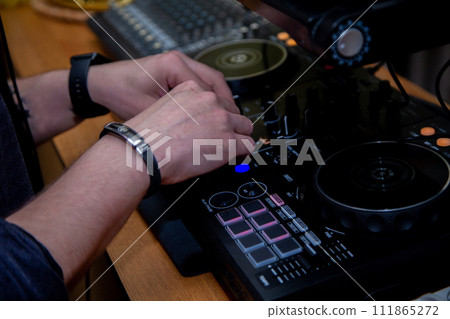 A DJ in a nightclub at the control panel adjusts the music. Music is playing, creating an atmosphere. High quality photo A DJ in a nightclub at the control panel adjusts the music. Music is playing, creating an atmosphere. High quality photo 111865272