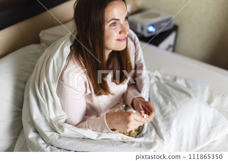 Woman Eating Breakfast in Bed Contentedly Woman Eating Breakfast in Bed Contentedly 111865350