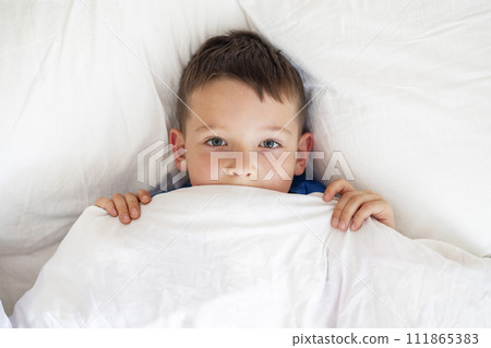 Young Boy Peeking from White Bedding 111865383
