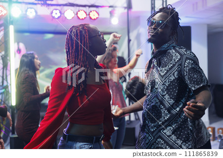 Relaxed african american man and woman dancers partying on nightclub dancefloor. Young boyfriend and girlfriend couple dancing together, having fun and celebrating in club Relaxed african american man and woman dancers partying on nightclub dancefloor. Young boyfriend and girlfriend couple dancing together, having fun and celebrating in club 111865839