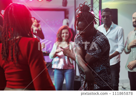 African american couple showing moves on crowded dancefloor in nightclub. Man and woman carefree dancers improvising dance battle for young people at discotheque party in club 111865878