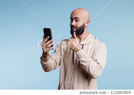 Young arab man showing thumb up while speaking in video call using smartphone. Person making approve sign while having online remote conversation in mobile phone videoconference 111865904