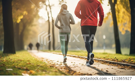 Two people jogging in a park at sunset, exemplifying outdoor fitness and an active lifestyle amidst an autumnal setting Two people jogging in a park at sunset, exemplifying outdoor fitness and an active lifestyle amidst an autumnal setting 111865927