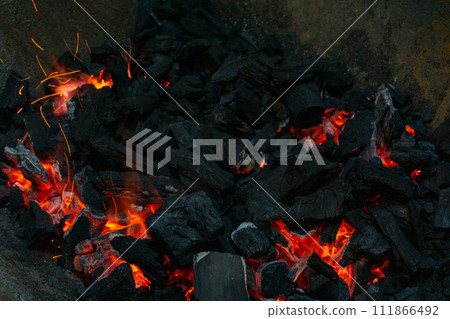 Coals with sparks in a huge old metal grill Coals with sparks in a huge old metal grill 111866492