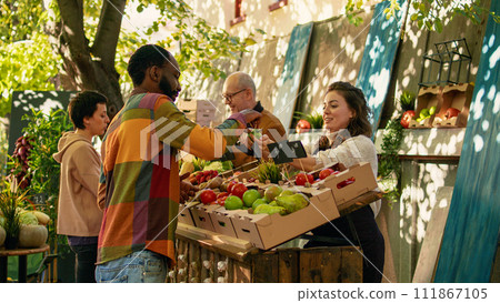 Female farmer giving free apple samples to clients for food tasting, enjoying bio products sampling at local greenmarket. Woman cutting slices of fruits to give to customers, business owner. 111867105
