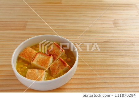 A bowl of grained corn soup and sliced toast 111870294