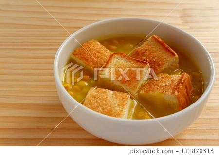 A bowl of grained corn soup and sliced toast 111870313