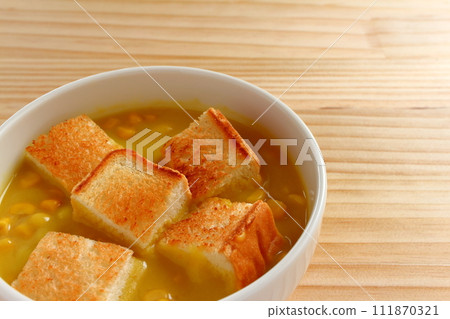 A bowl of grained corn soup and sliced toast 111870321