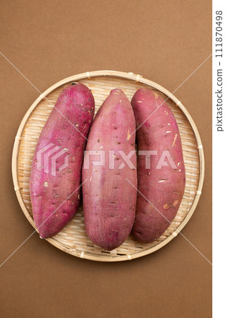 Sweet potatoes on a brown background in a colander 111870498