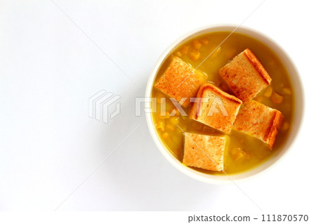 A bowl of grained corn soup and sliced toast 111870570