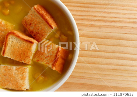 A bowl of grained corn soup and sliced toast 111870632