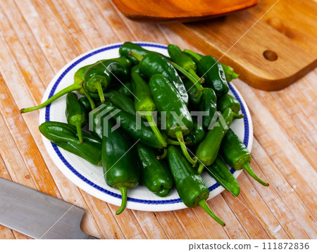 Lots of green peppers on wooden cutting board Lots of green peppers on wooden cutting board 111872836