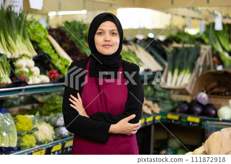 Muslim woman seller in hijab stands with arms crossed on chest and waits for customers 111872918
