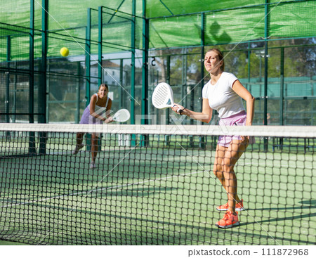 Two women tennis players playing padel Two women tennis players playing padel 111872968