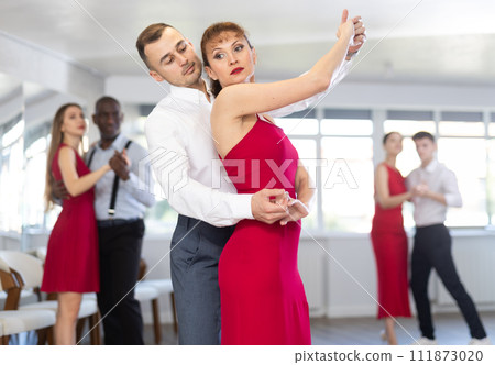 Man dancing merengue with woman in red in latin dance class Man dancing merengue with woman in red in latin dance class 111873020