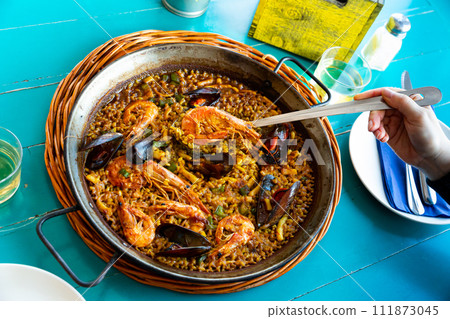 Cook serving seafood paella 111873045