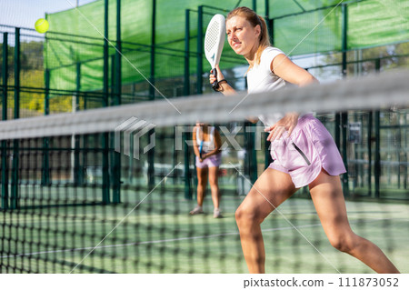 European woman padel tennis player trains on the outdoor court 111873052