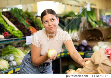 Young woman shopper chooses onions in supermarket 111873116