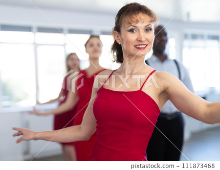 Young girls in red dress dancing together with multinational men slow ballroom dances in pairs in ball room at dance salon Young girls in red dress dancing together with multinational men slow ballroom dances in pairs in ball room at dance salon 111873468