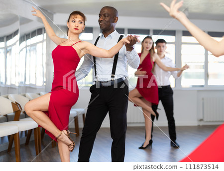African American performing kizomba with woman in red in dance studio African American performing kizomba with woman in red in dance studio 111873514