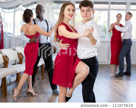 Young guy and graceful woman rehearsing elegant tango in pair Young guy and graceful woman rehearsing elegant tango in pair 111873619
