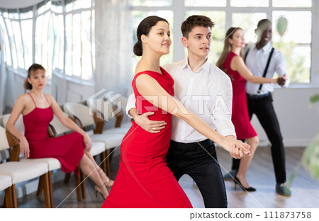 Smiling couple enthusiastically dancing social latin cha-cha-cha dance in dance salon 111873758