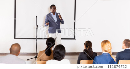Smiling african american lecturer speaking to businesspeople at seminar 111874712