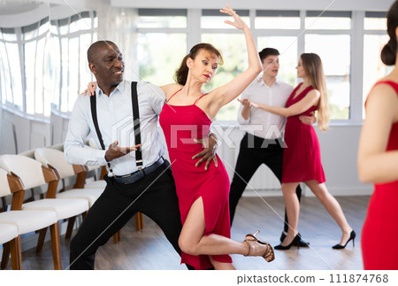 African American performing kizomba with woman in red in dance studio African American performing kizomba with woman in red in dance studio 111874768