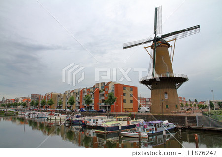 A streetscape with windmills along a canal in Rotterdam, the central city of South Holland in the Netherlands in Western Europe A streetscape with windmills along a canal in Rotterdam, the central city of South Holland in the Netherlands in Western Europe 111876242