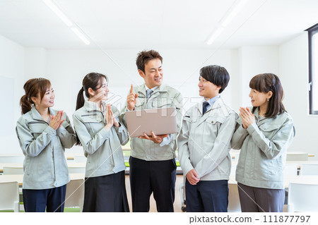 Profile of employees and staff wearing work clothes holding a laptop computer and having a meeting at a factory / construction company 111877797