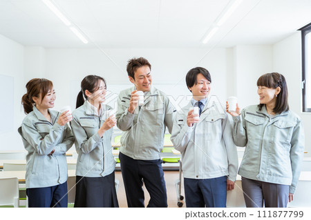 Employees/staff in work clothes chatting while drinking coffee during a break at a small to medium-sized company such as a factory or construction company. Employees/staff in work clothes chatting while drinking coffee during a break at a small to medium-sized company such as a factory or construction company. 111877799