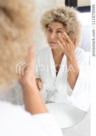 Young Woman Performing Skin Care Routine in Bathroom Mirror Young Woman Performing Skin Care Routine in Bathroom Mirror 111878086