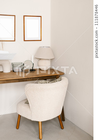 Cozy workspace with wooden desk and upholstered armchair in a Scandinavian minimalist style home Cozy workspace with wooden desk and upholstered armchair in a Scandinavian minimalist style home 111878446